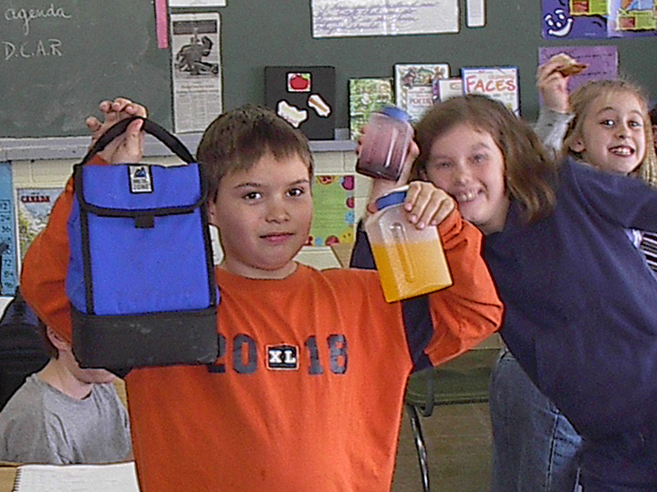 Student holding up a cloth lunchbag and reusable container