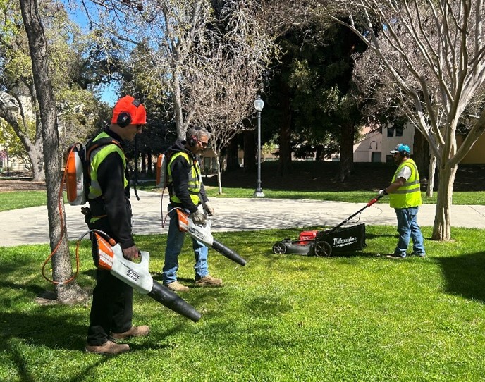 Workers in park with electric leaf blowers
