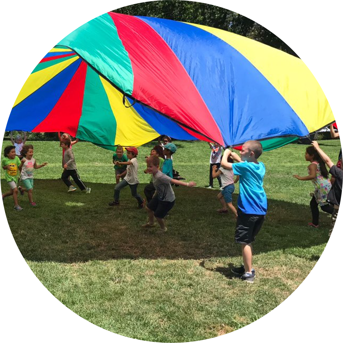 children playing in field with colorful parachute